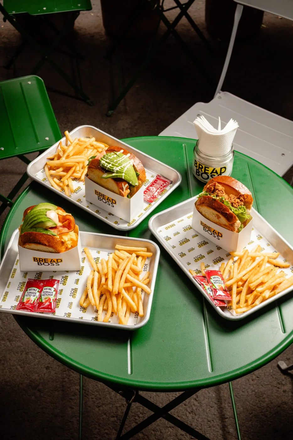 Sandwiches y papas de Bread Boss sobre una mesa verde