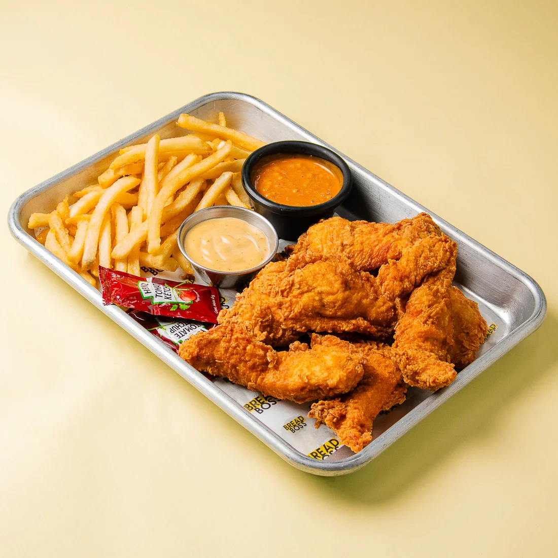Chicken Tenders crujientes con papas fritas y dos salsas de Bread Boss